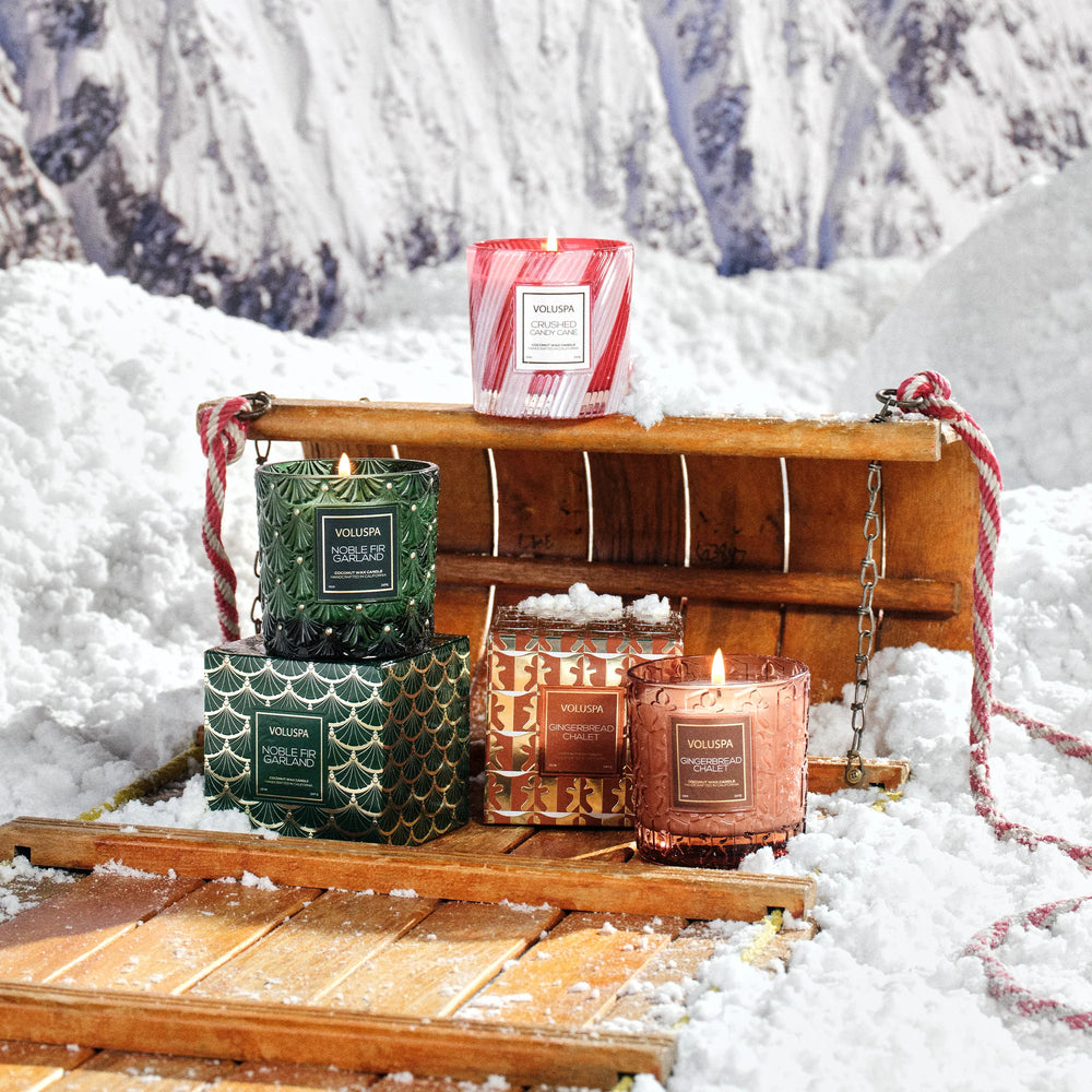 Crushed Candy Cane Luxe Classic Candle displayed with Voluspa holiday candles in a festive snowy Christmas scene