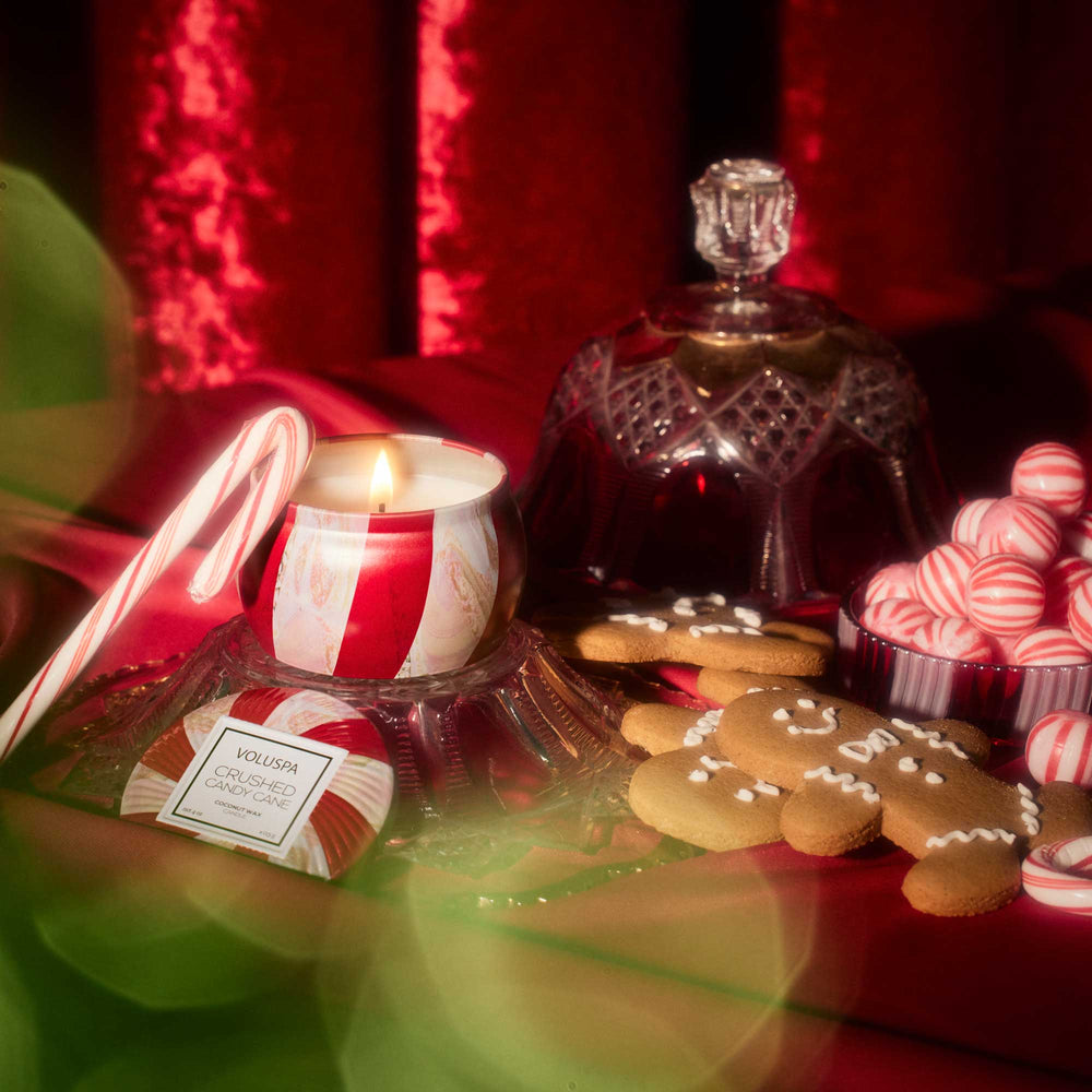 Crushed Candy Cane Mini Tin Candle lit among candy canes, peppermint candies and festive Christmas décor
