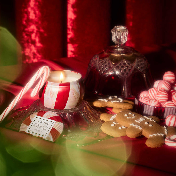 Crushed Candy Cane Mini Tin Candle lit among candy canes, peppermint candies and festive Christmas décor