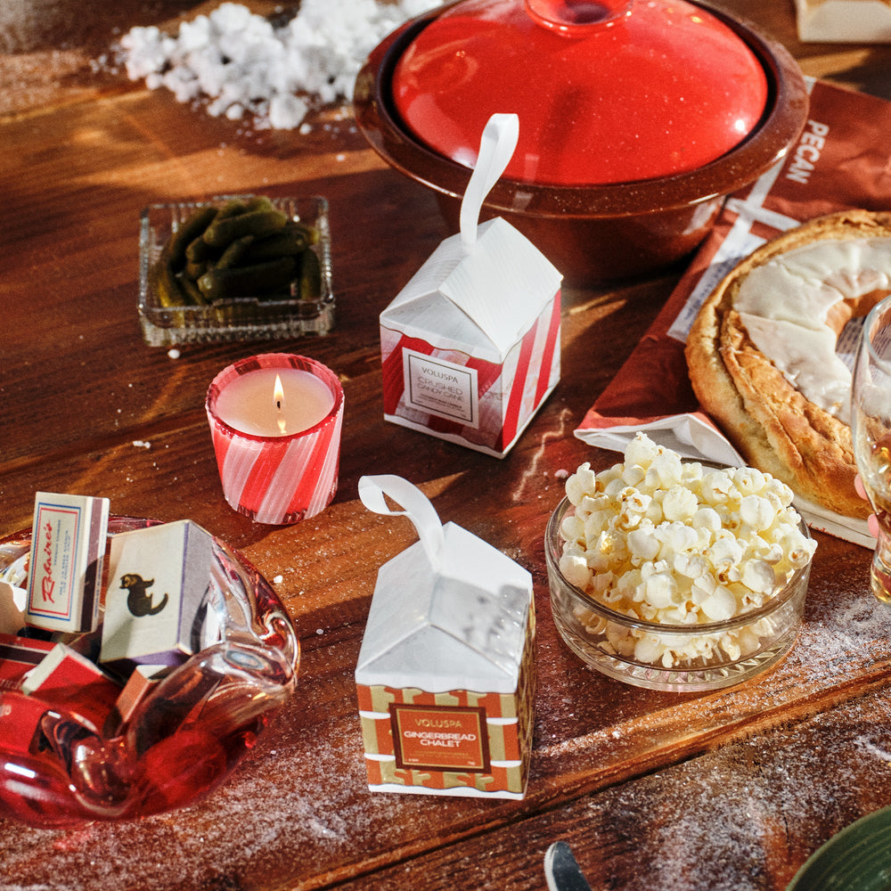 Crushed Candy Cane Ornament Pedestal Candle lit on a festive holiday table with Voluspa Christmas candles