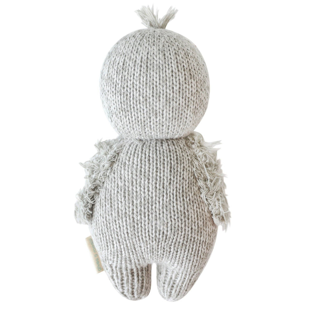 Flat image of the back of Cuddle+Kind's light gray plush Baby Penguin on a clean white background