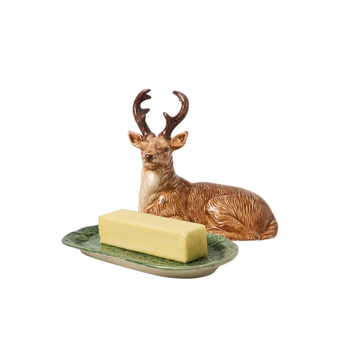 Ceramic deer butter dish with sculpted stag cover and green woodland tray, shown with a stick of butter.

