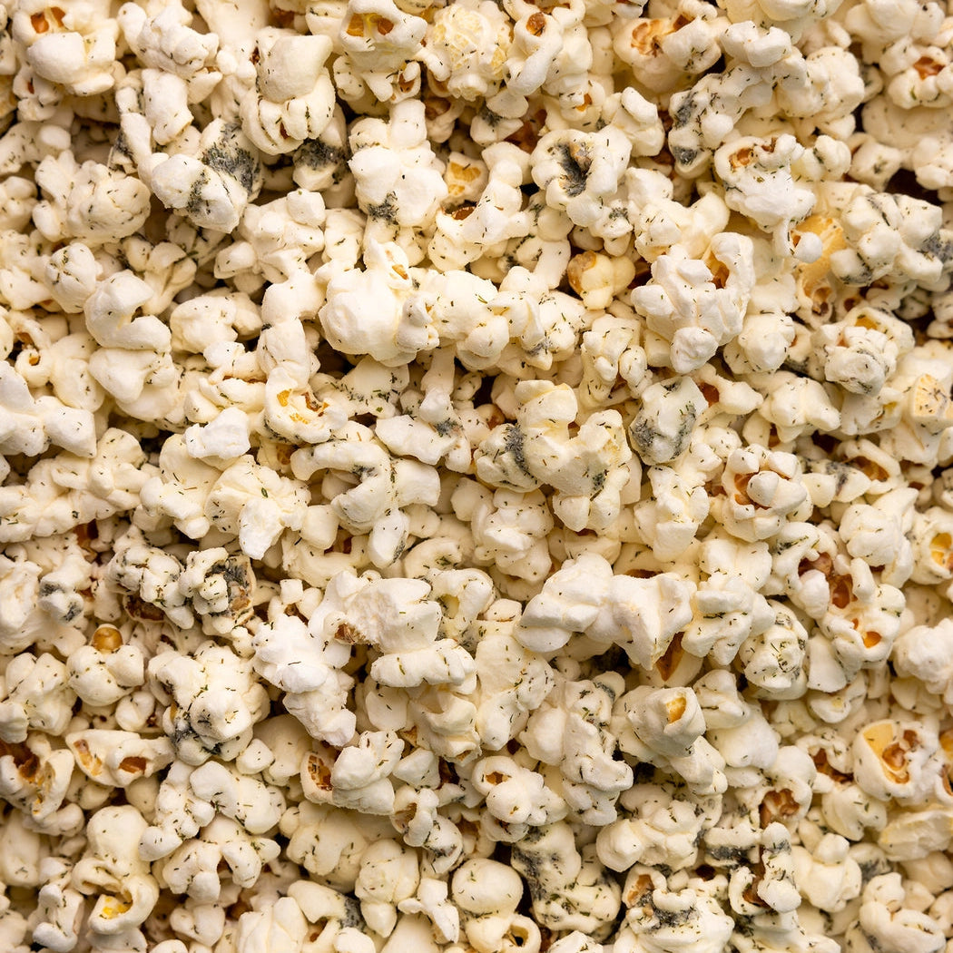Close-up of white cheddar Dill Pickle Popcorn seasoned with crisp dill