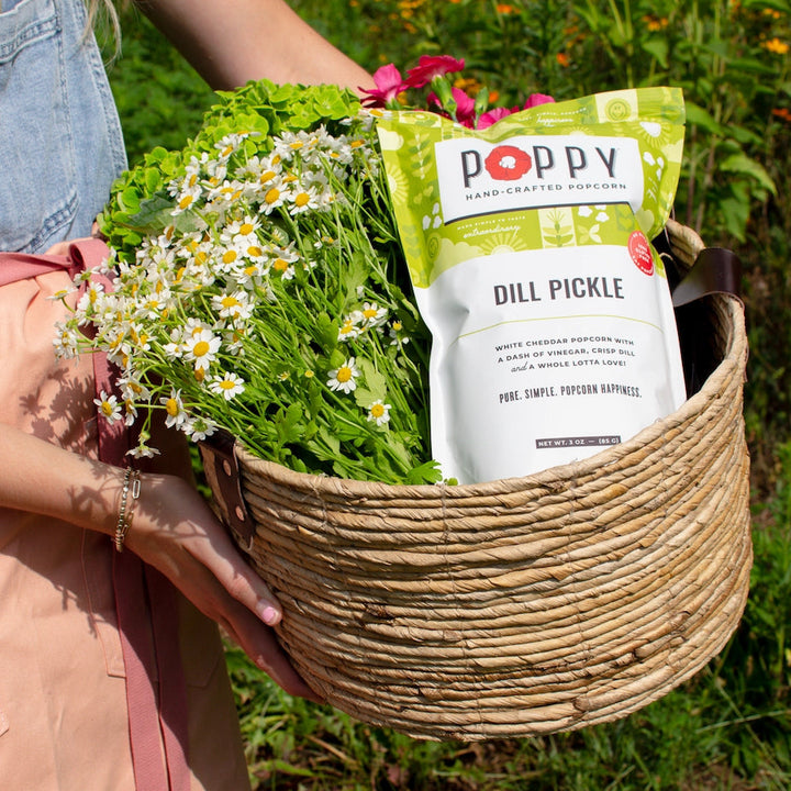Poppy Dill Pickle Hand-Crafted Popcorn displayed in a basket with fresh flowers