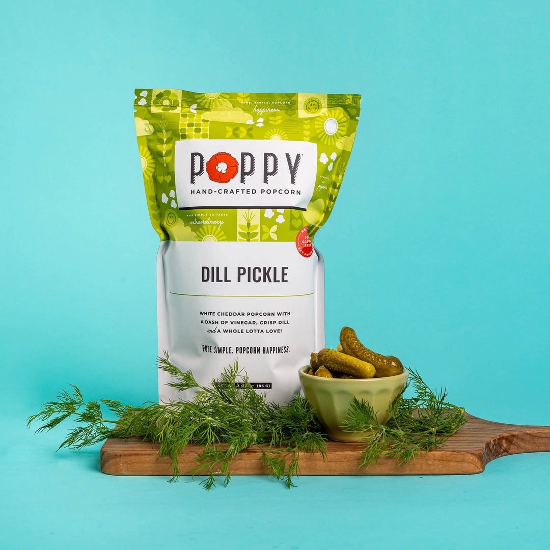 Poppy Dill Pickle Hand-Crafted Popcorn displayed with pickles and fresh dill