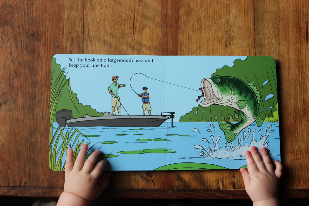 Good Luck Fishermen children's book interior spread showing a largemouth bass jumping beside two anglers in a boat