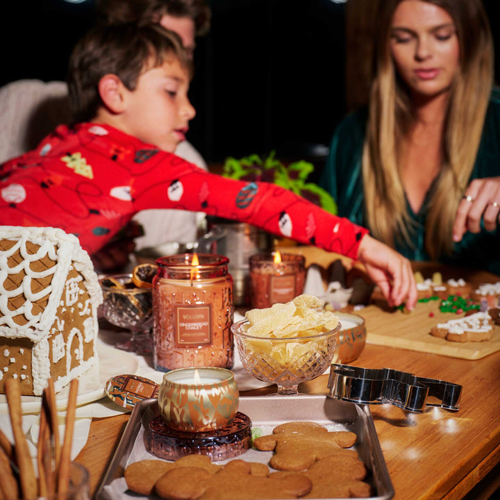 Gingerbread Chalet Mini Tin Candle by Voluspa styled with gingerbread cookies and coordinating holiday candles