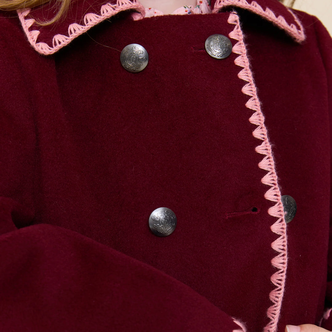 Close-up of Girls Beck Peacoat Burgundy featuring decorative metal buttons and contrasting pink trim
