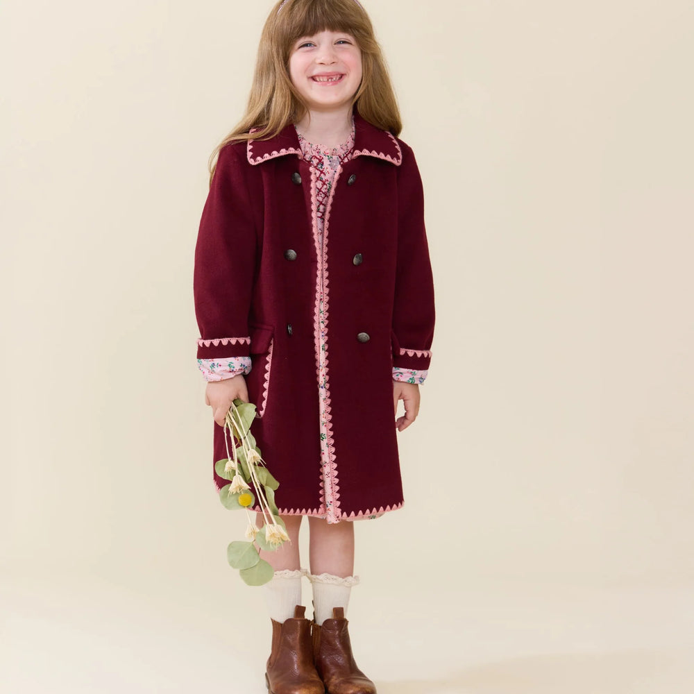 Girl wearing the Girls Beck Peacoat Burgundy with pink trim and double-breasted button front