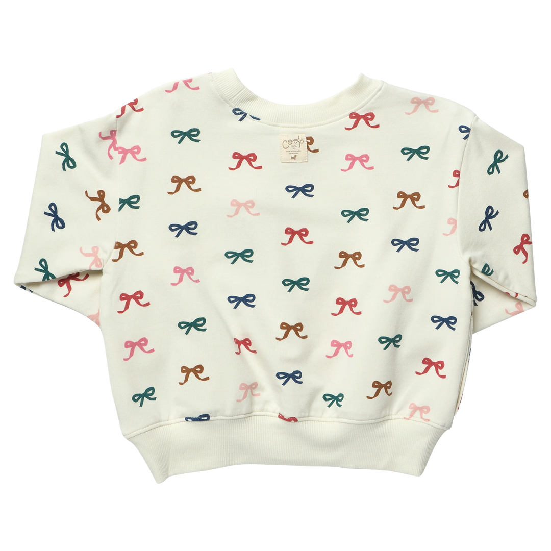Back view of cream girls sweatshirt featuring an all-over colorful bow print and ribbed hem, cuffs and crew neckline