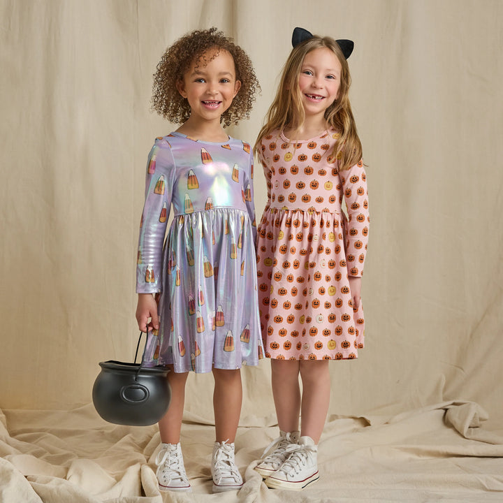 Girls modeling festive Halloween dresses, including an iridescent lavender candy corn dress with long sleeves and a twirl skirt.