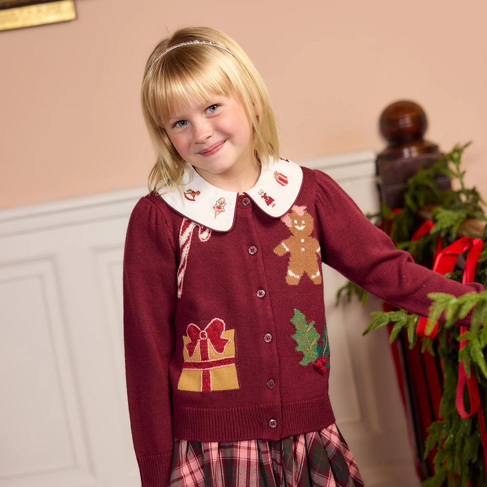 Young girl wearing the Pink Chicken Girls Constance Sweater in burgundy paired with a festive tartan skirt and holiday embroidered collar.