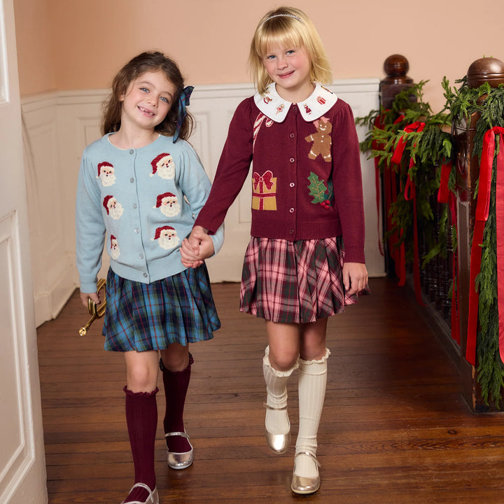 Girl wearing the light blue Tossed Santas Constance Sweater with a blue plaid skirt for a festive Christmas outfit