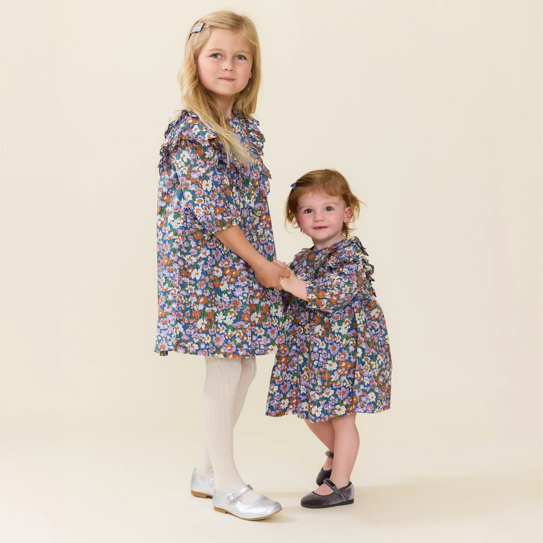 Girls wearing matching True Blue Sketched Floral dresses with colorful floral print and ruffle details