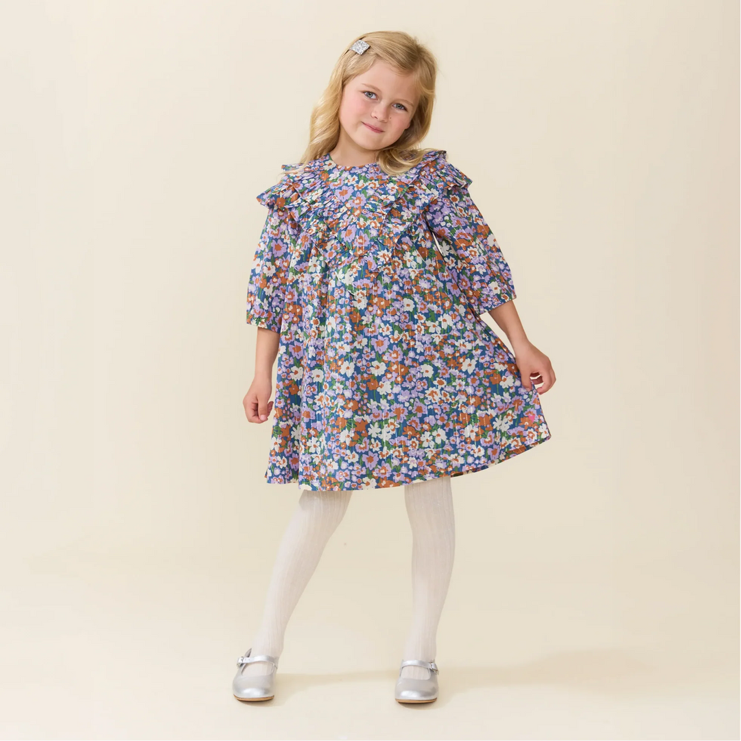 Girl wearing the Girls Everly Dress True Blue Sketched Floral with statement ruffle detailing