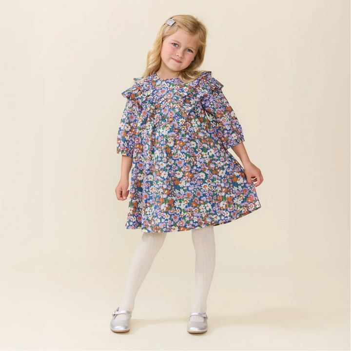 Girl wearing the Girls Everly Dress True Blue Sketched Floral with statement ruffle detailing