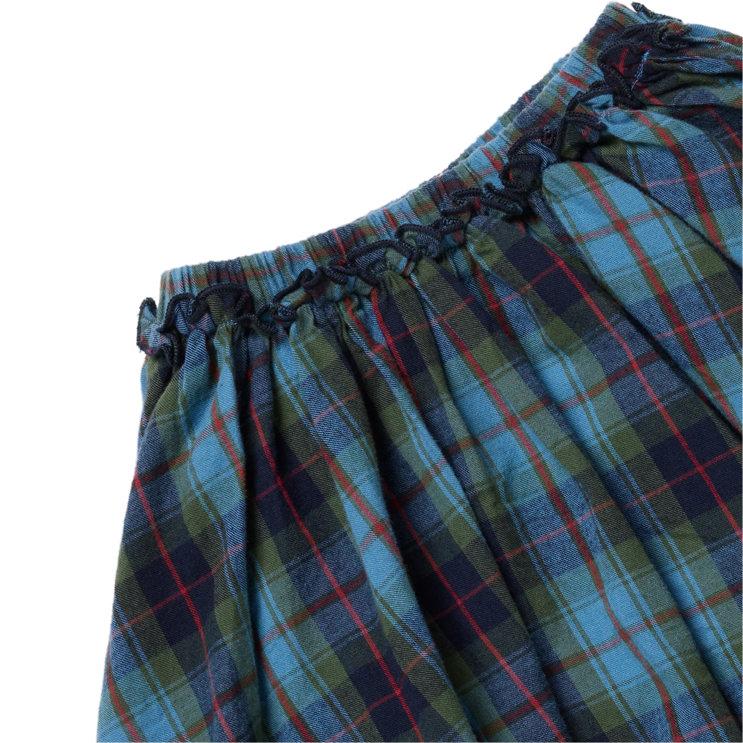 Close-up of Pink Chicken Gianna Skirt showing blue tartan plaid fabric, gathered waistband, and decorative ruffle trim