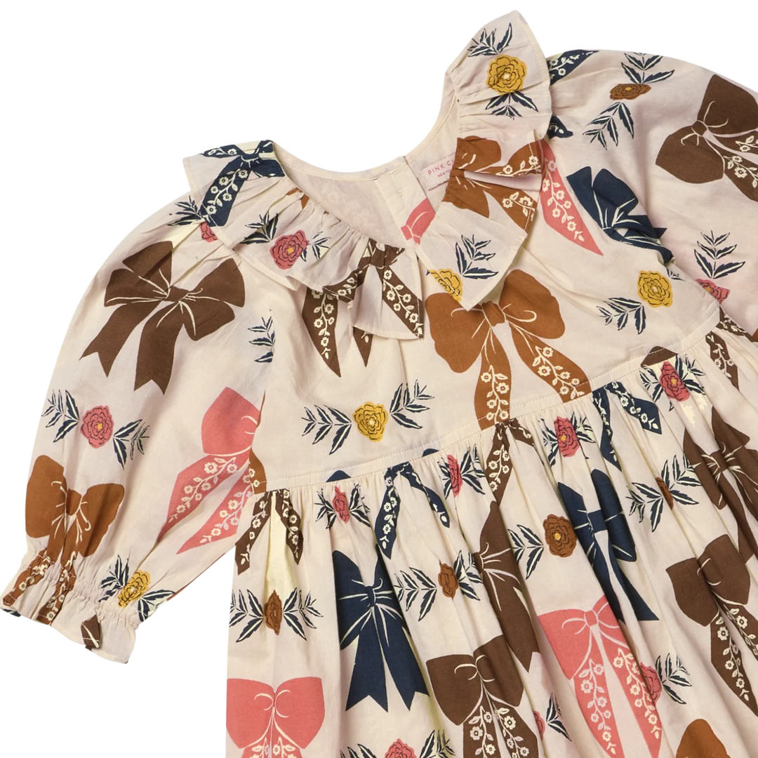Close-up of Girls Harvest Bow Dress featuring ruffled collar and brown, pink and navy bow print