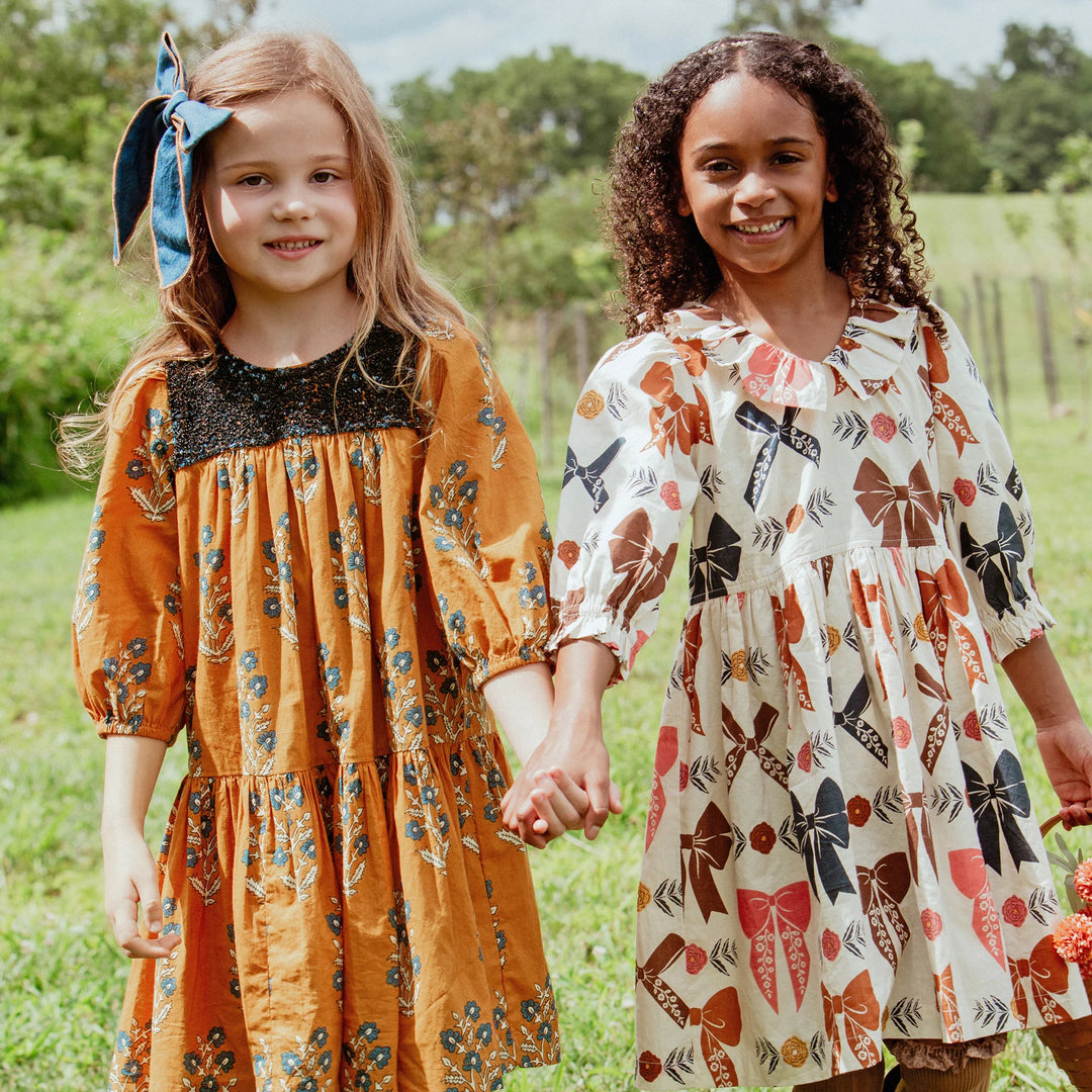 Girl wearing Girls Harvest Bow Dress with colorful bow print for a charming fall outfit