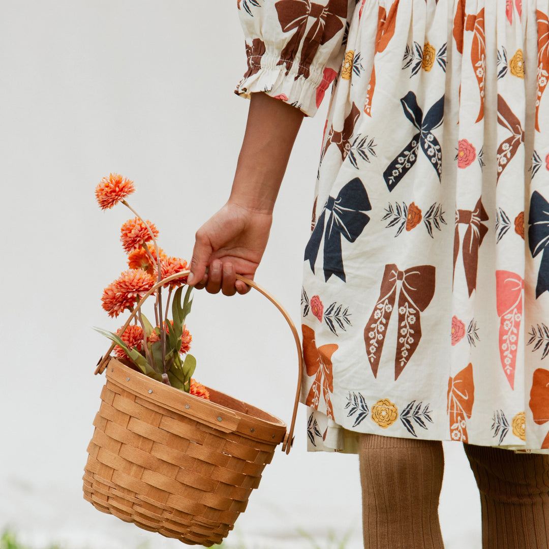 Detail of Girls Harvest Bow Dress with gathered skirt, bow print, floral accents and ruffled sleeve cuffs