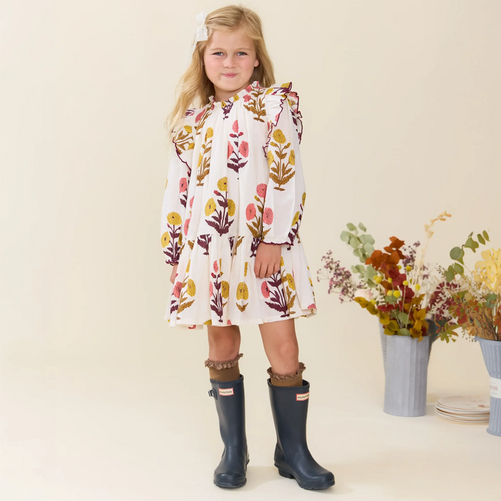 Girl wearing the Girls Harvest Dandelion Dress styled with knee-high boots for fall