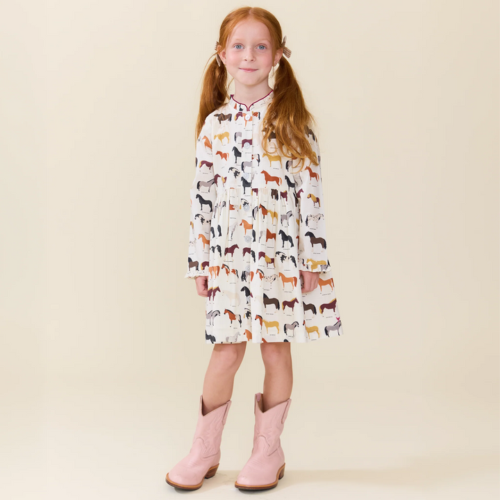 Girl modeling ivory Horse Print Dress with colorful horse breed pattern and pink cowboy boots