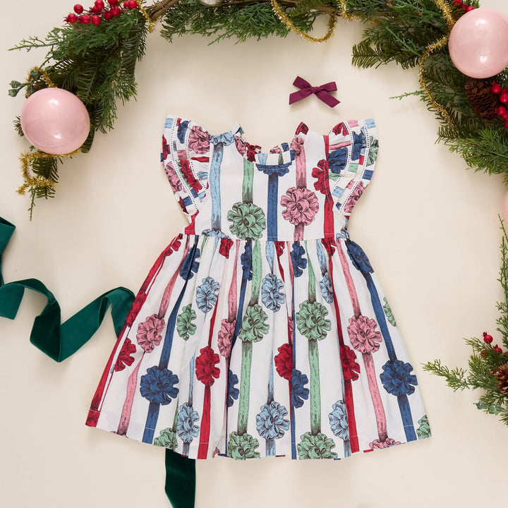 Pink Chicken Girls Present Bows Dress styled with Christmas greenery, ornaments, and festive holiday accessories