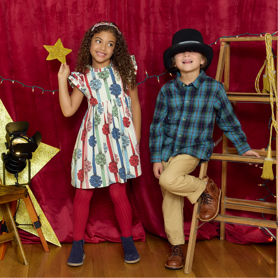 Girl wearing Pink Chicken Present Bows Christmas Dress with colorful ribbons and flutter sleeves during a holiday photoshoot