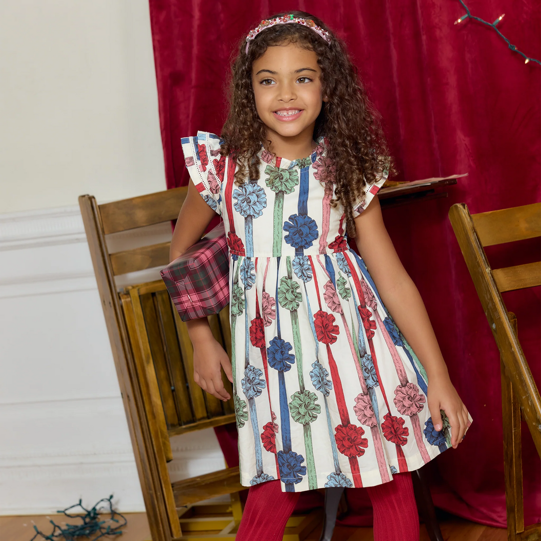 Young girl wearing Pink Chicken Present Bows Jennifer Dress with colorful gift ribbon print and double ruffle sleeves