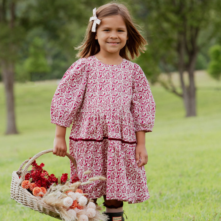Girl wearing the Girls Maribelle Dress in Burgundy Climbing Floral outdoors for fall