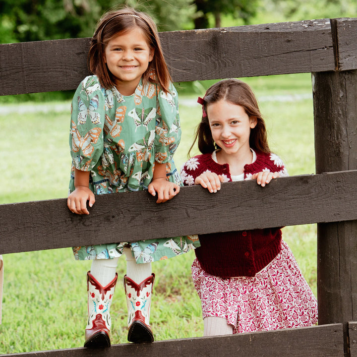 Girl wearing Girls Maribelle Dress Green Butterflies outdoors with boots