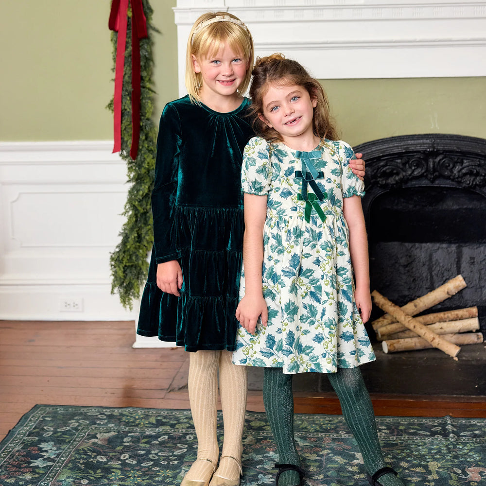 Girl wearing the Pink Chicken Evergreen Velour Pearl Dress with cream tights and gold shoes for a festive holiday look