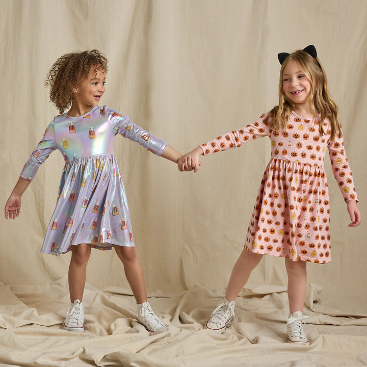 Girl modeling a pink pumpkin Halloween dress with long sleeves and jack-o&