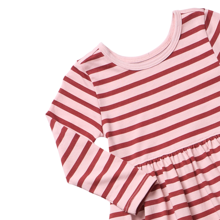 Close-up of girls pink striped dress showing red horizontal stripes, round neckline, long sleeves, and gathered waist detail.