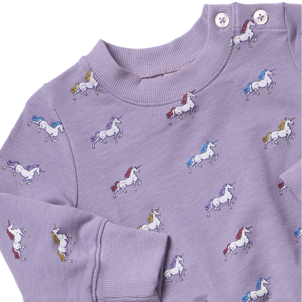 Close-up of girls purple unicorn sweatshirt showing colorful white unicorns, ribbed neckline and shoulder button details.