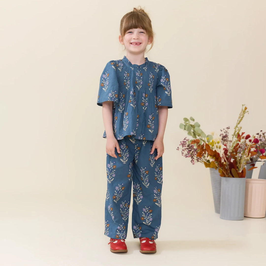 Girl modeling Balsam Dewdrop floral Theodore Pants with matching blue floral blouse
