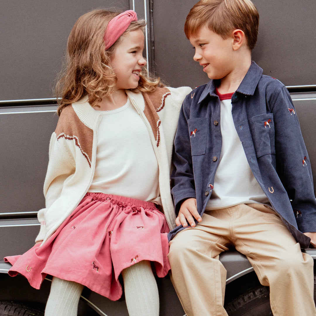 Girl wearing cream and brown Girls Western Sweater styled with pink skirt beside boy in western outfit
