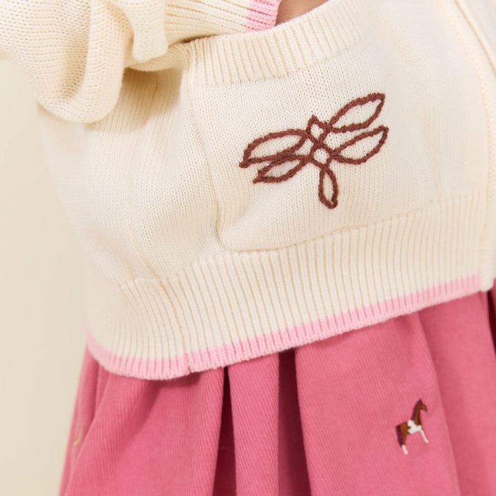 Close-up of embroidered pocket on cream Girls Western Sweater with brown stitching and pink trim