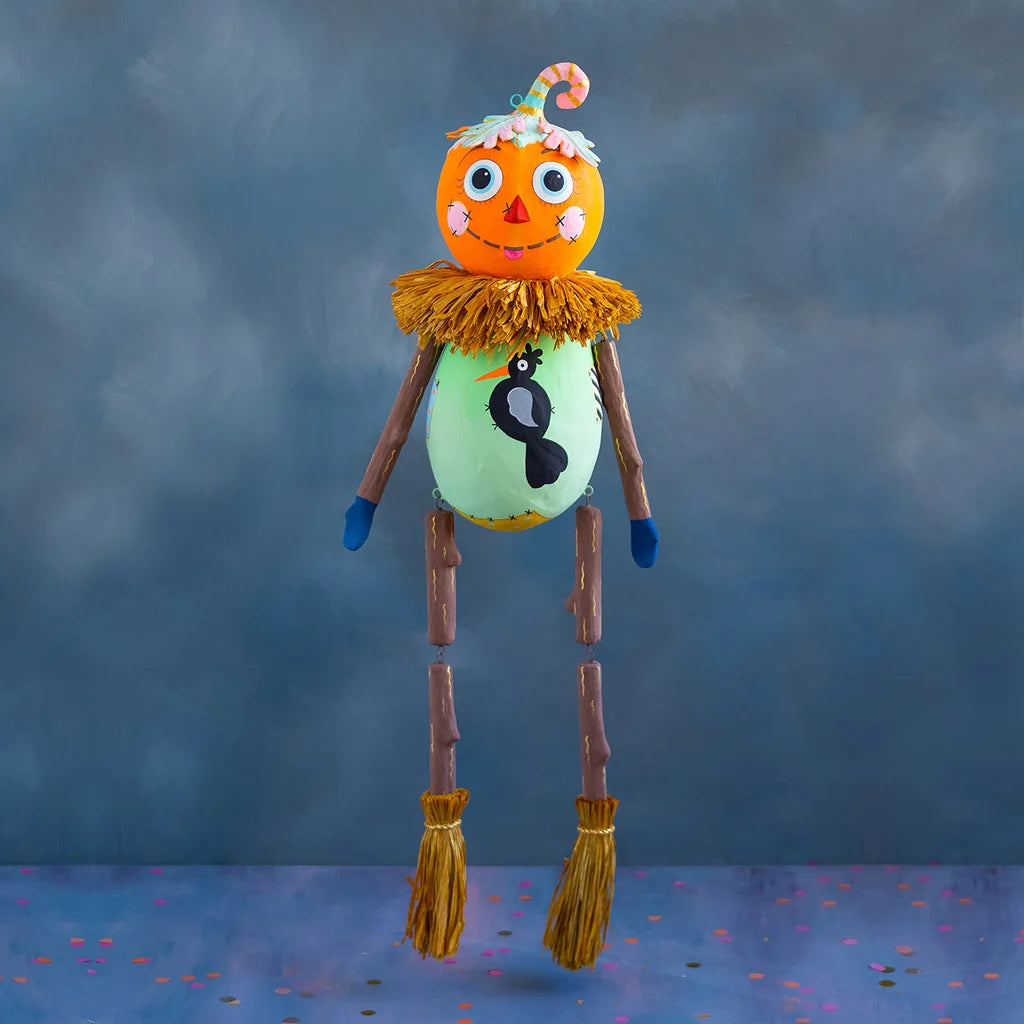Whimsical baby squash Halloween display featuring a colorful squash character with long dangling legs and straw accents.