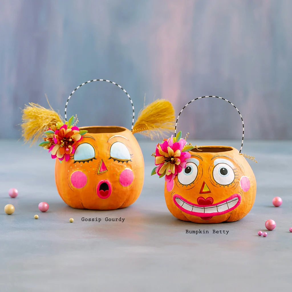 Glitterville Bumpkin Betty and Gossip Gourdy pumpkin buckets featuring playful faces, colorful floral accents, and whimsical Halloween details. Name labels are displayed under each bucket for easy distinguishing. 