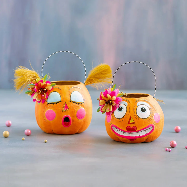 Glitterville Bumpkin Betty and Gossip Gourdy pumpkin buckets featuring playful faces, colorful floral accents, and whimsical Halloween details.