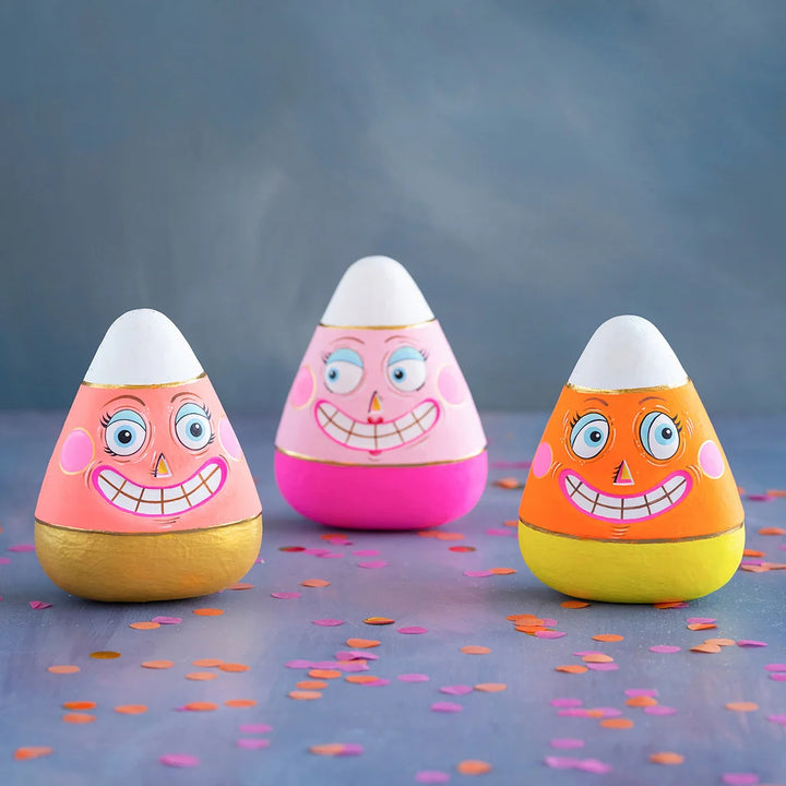Glitterville Candice, Kettle and Carl candy corn figurines featuring colorful pink, orange, yellow, and white designs with playful smiling faces.