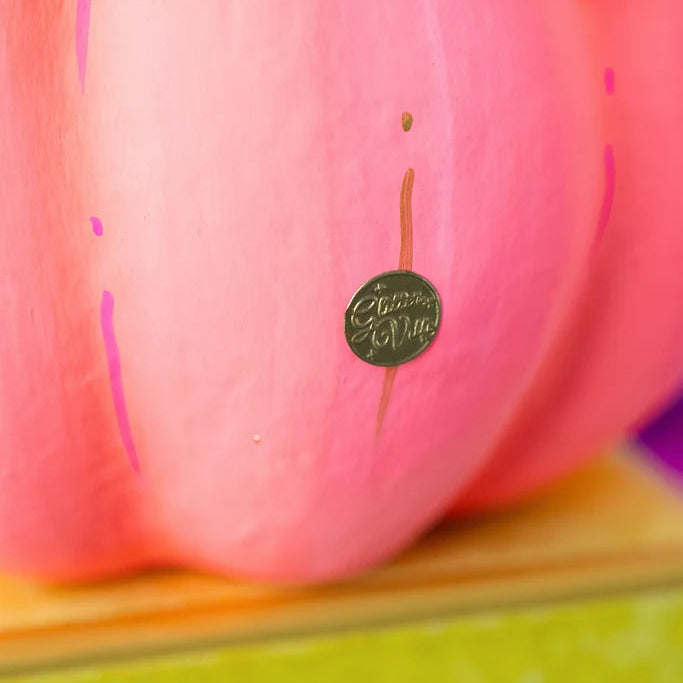 Glitterville Coral Pumpkin Pixie close-up showing the signature brand coin detail on the pumpkin.