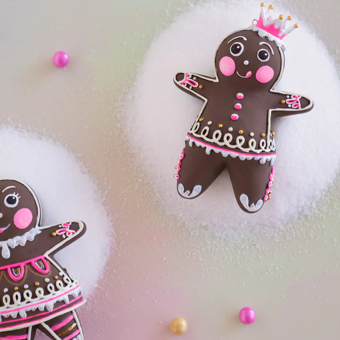 Glitterville Dough and Dippsy gingerbread Christmas ornaments shown in a detailed close-up, highlighting their brown gingerbread designs with intricate pink, white, and gold icing, decorative looping patterns, scalloped icing trim, pink buttons, floral accents, and Dough’s signature pink crown with gold-tipped points.
