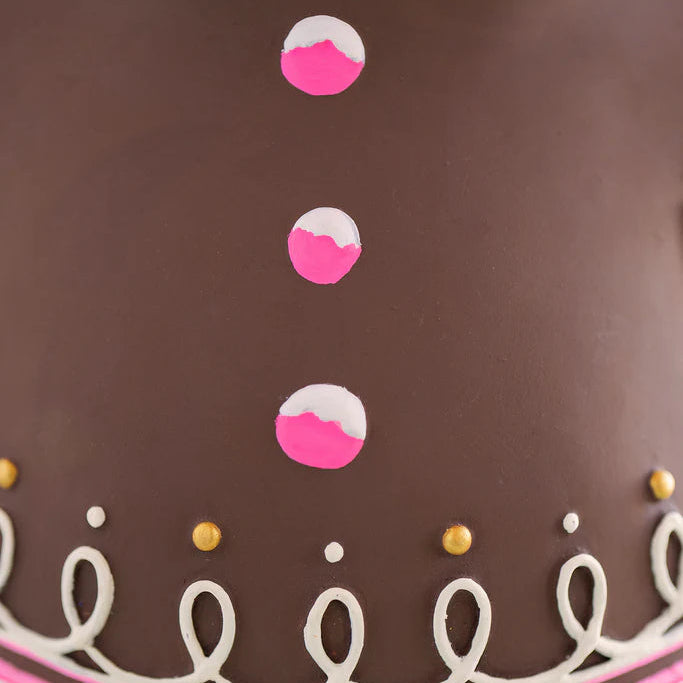 Glitterville Dough gingerbread figure close-up showcasing three pink and white candy-style buttons on his brown gingerbread body, surrounded by intricate white looping icing, pink accents, and small gold and white decorative icing dots.