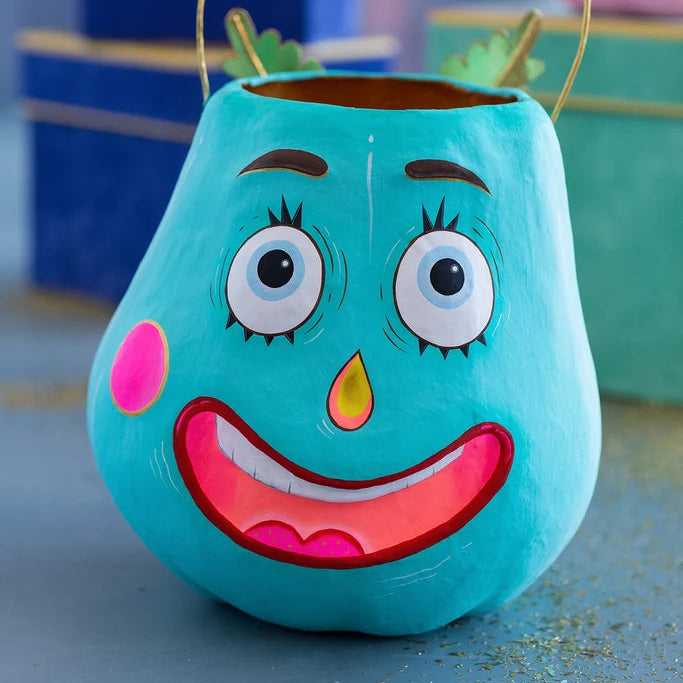 Glitterville Gourdy Pumpkin Pixie Bucket in turquoise blue with large expressive eyes, pink cheeks, a bright pink smile, and an open top with a wire handle.