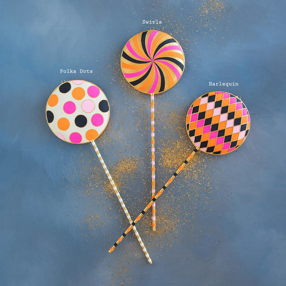 Glitterville Halloween lollipop display set featuring three whimsical oversized candy lollipops in colorful swirl, polka dot, and pink-orange checkerboard patterns with coordinating striped sticks and glitter accents. Pattern labels are displayed for easy distinguishing. 