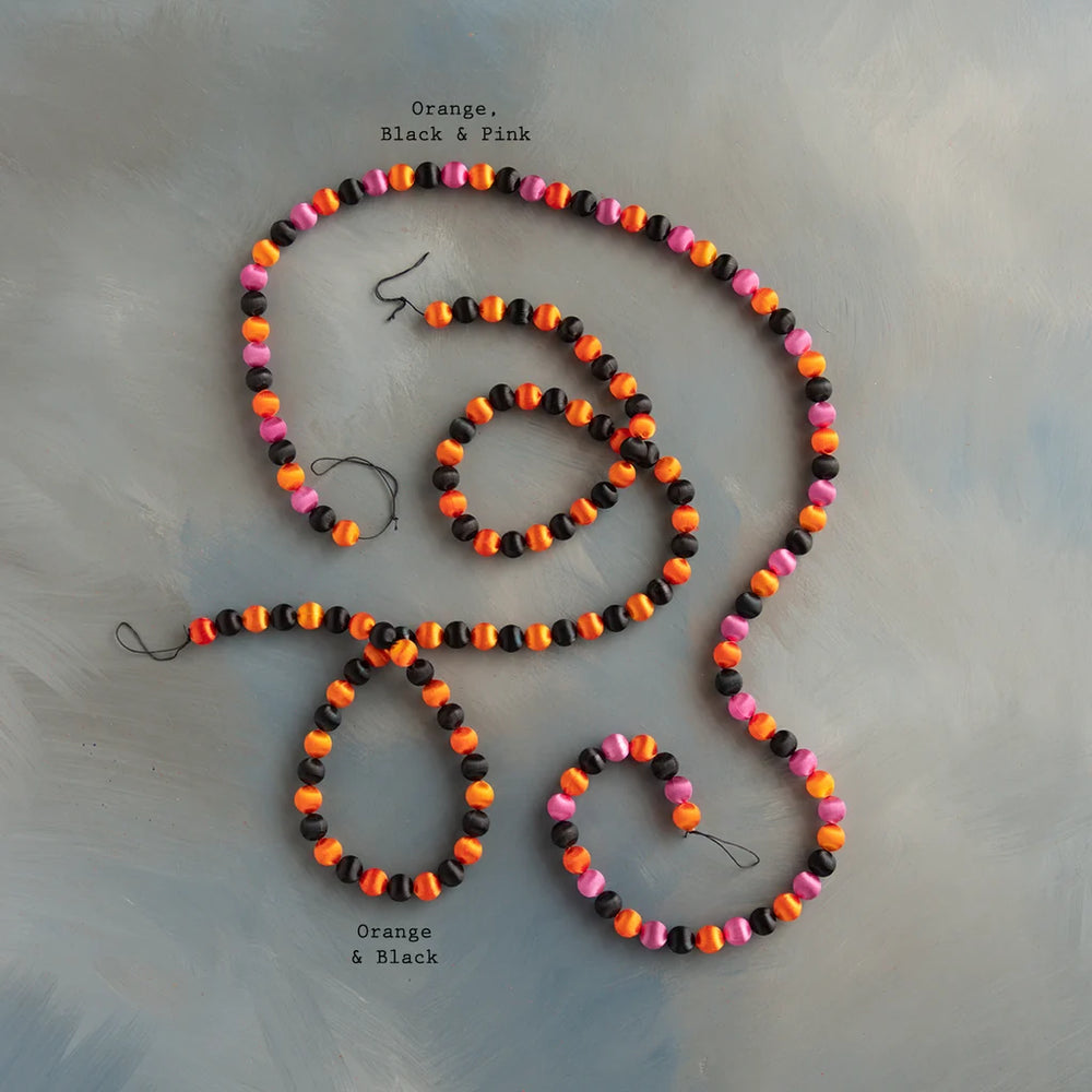 Glitterville Halloween silk ball garland set featuring colorful orange, black, and hot pink silk balls arranged in a festive strand, perfect for Halloween tree decorating, mantels, shelves, party backdrops, and playful seasonal displays. Color combination label displayed near each garland for easy distinguishing. 