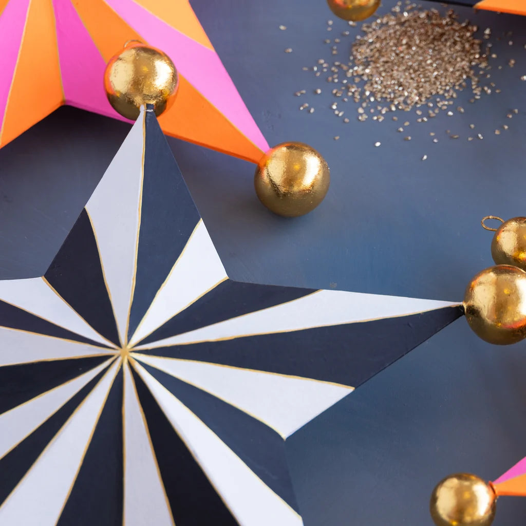 Glitterville Halloween Stripe Star Set small size detail featuring black and white striped star with gold ball accents, pink and orange star in background, and glitter.