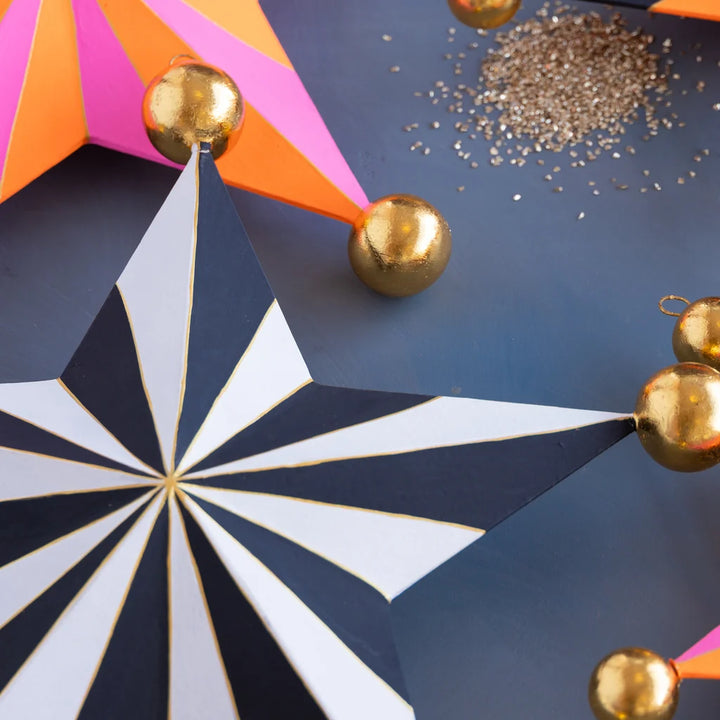 Glitterville Halloween Stripe Star Set small size detail featuring black and white striped star with gold ball accents, pink and orange star in background, and glitter.